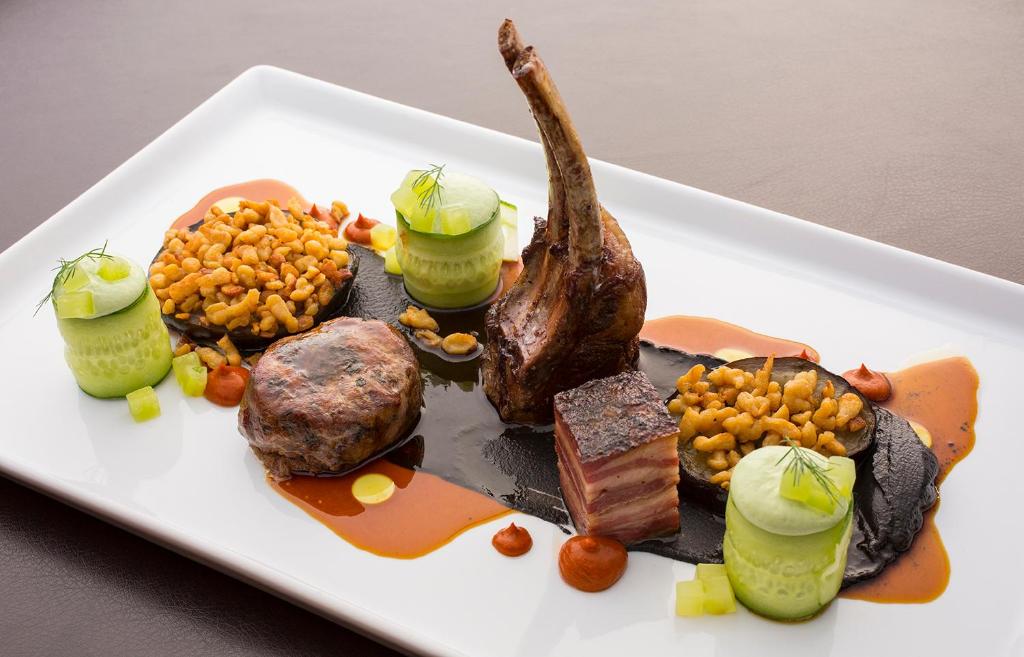 a plate of food with meat and vegetables on a table at Ciampedie Luxury Alpine Spa Hotel in Vigo di Fassa