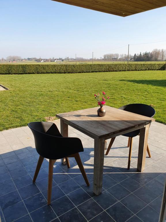 a wooden table and two chairs on a patio at Vakantiehuis Onverbloemd in Tielt