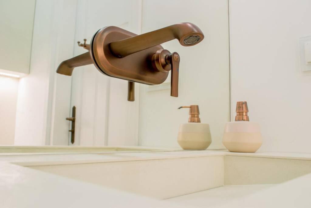 a bathroom sink with a copper faucet and a mirror at APARTAMENT Inspiracja in Mrągowo