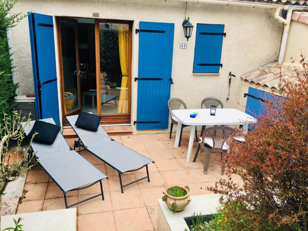 een patio met blauwe deuren en een tafel en stoelen bij Maisonnette Provençal in Tourrettes