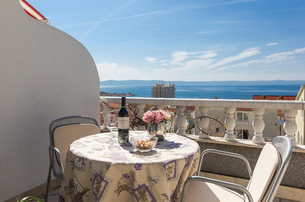 a table with a bottle of wine and flowers on a balcony at Apartments Erceg in Makarska