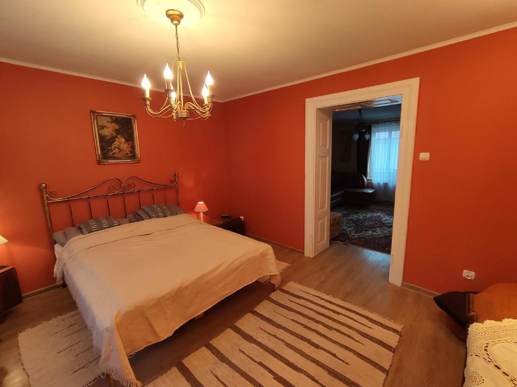 1 dormitorio con paredes de color naranja y 1 cama con lámpara de araña. en Dom pod Zegarem, en Przemyśl