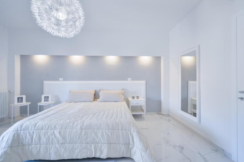 a white bedroom with a large bed and a mirror at New Central Apartment & Rooms in Montecatini Terme
