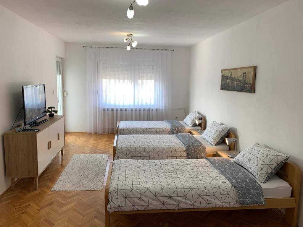 a bedroom with two beds and a television in it at Apartmani Nedim in Dubrave Gornje