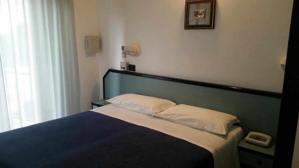 a bedroom with a bed with a blue head board at Hotel Caravelle in Riccione