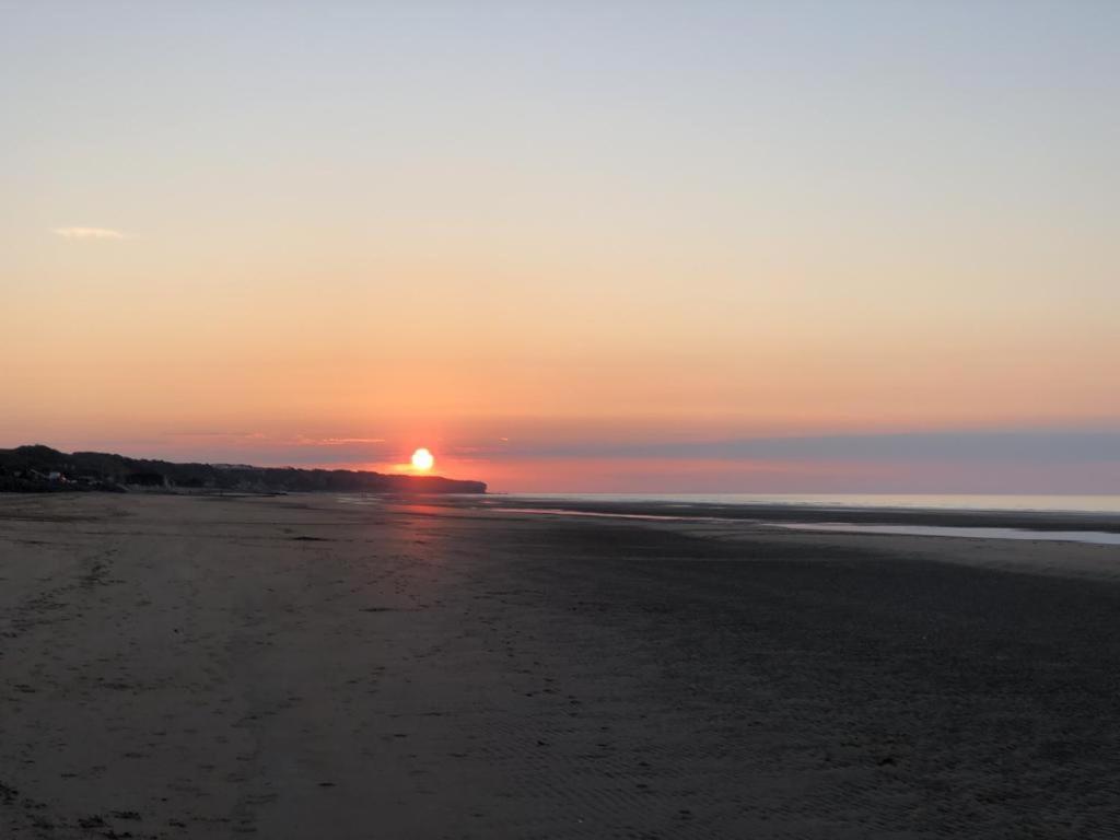 a sunset on the beach with the sun setting at Villa kahlo Omaha Beach in Colleville-sur-Mer