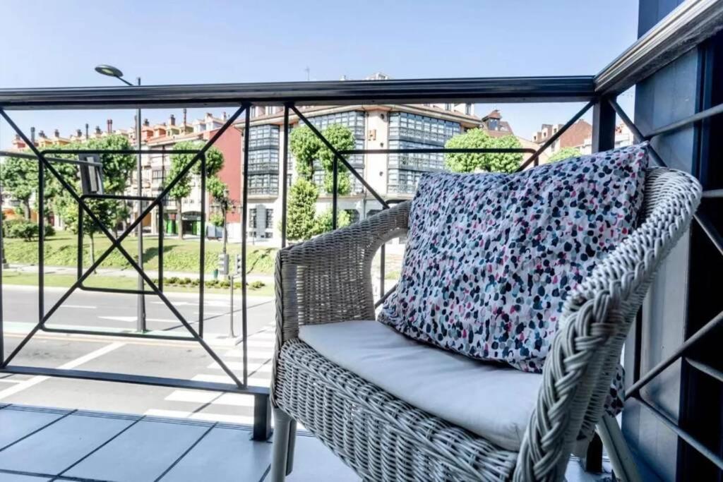 einen Korbstuhl auf einem Balkon mit einem Kissen in der Unterkunft EL BALCÓN DE CAMPO LOS PATOS in Oviedo