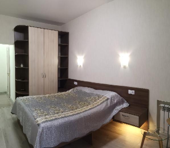 a bedroom with a bed and two lights on the wall at Апартаменты на Соборном с видом на парк in Zaporozhye
