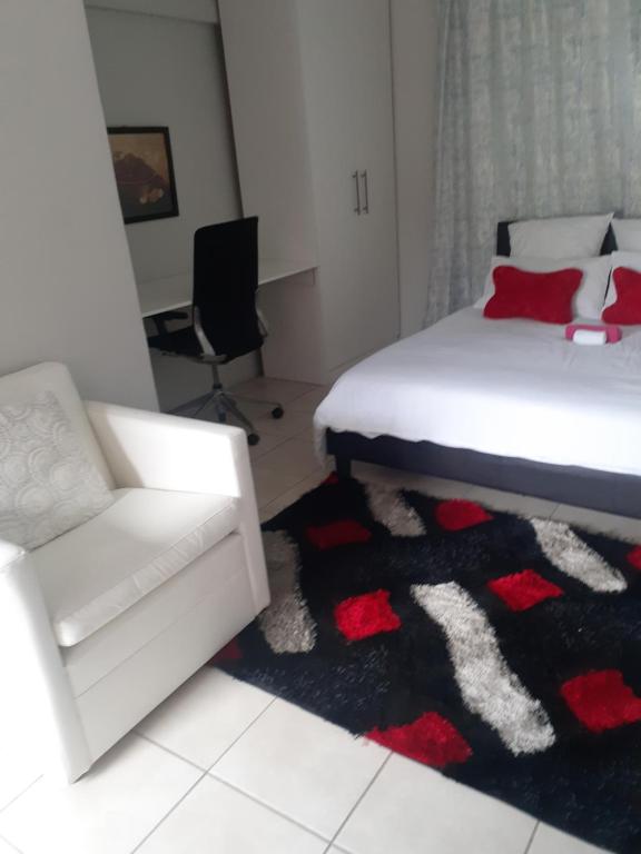 a bedroom with a bed and a couch and a chair at Ruros Guest House in Kempton Park