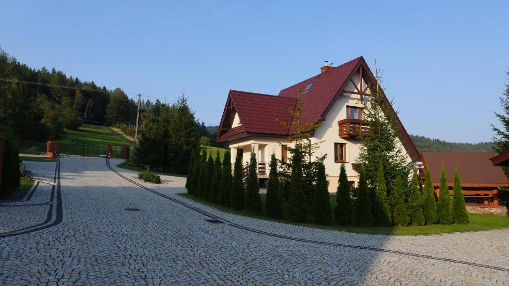 a white house with a red roof on a street at Miodowe Zacisze in Kamianna