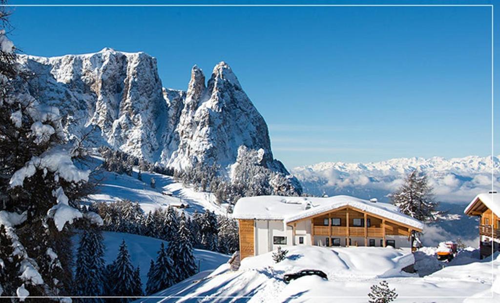 a ski lodge in the snow with a mountain at Hotel Chalet Dolomites in Alpe di Siusi