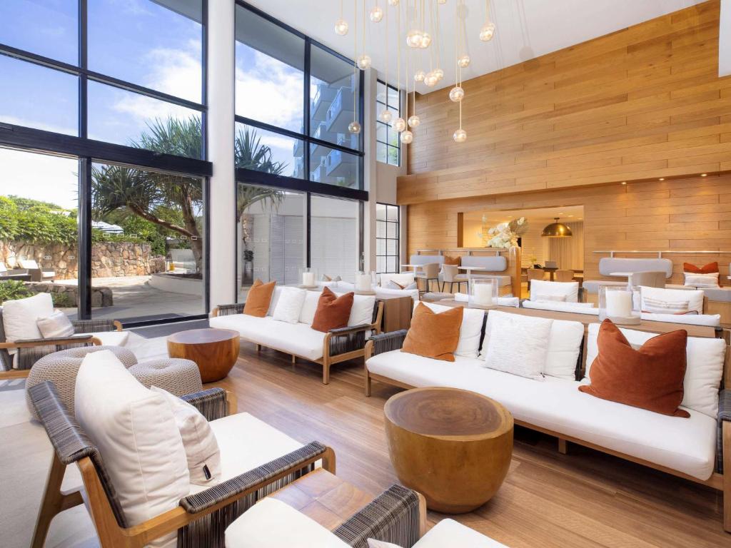 a lobby with white couches and tables and windows at Sofitel Noosa Pacific Resort in Noosa Heads