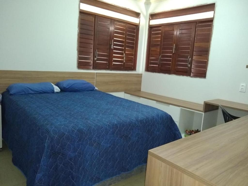 um quarto com uma cama azul e 2 janelas em Cond. Águas da Serra, Bananeiras em Bananeiras