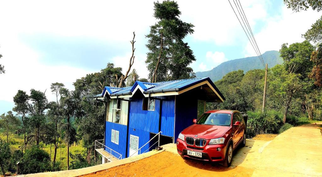 a red car parked in front of a blue house at Kithul Cottage in Nuwara Eliya