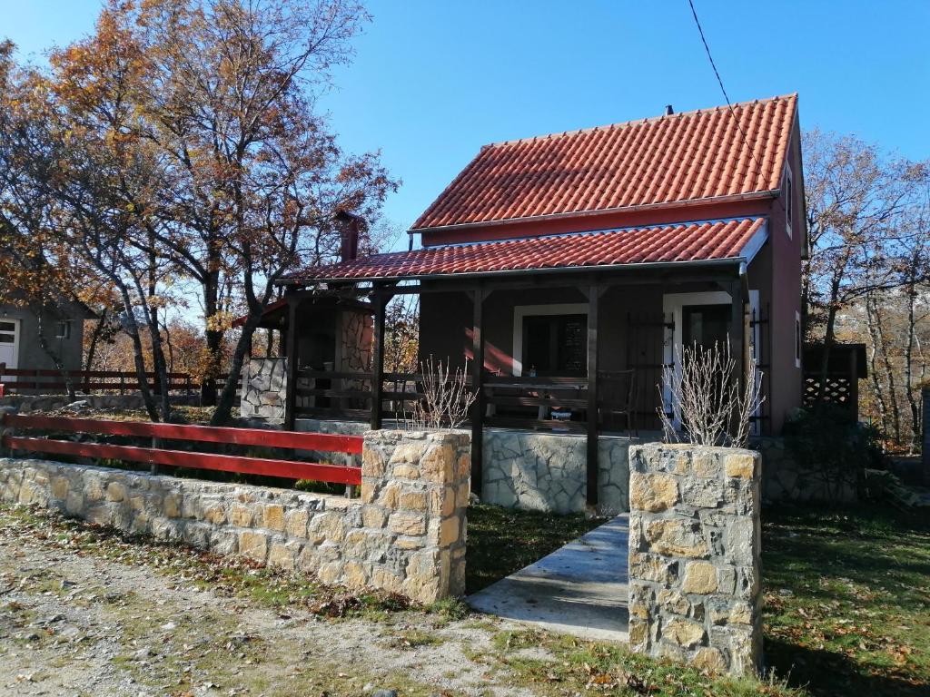 a small house with a stone wall and a roof at Holiday Home Nikolić in Njeguši