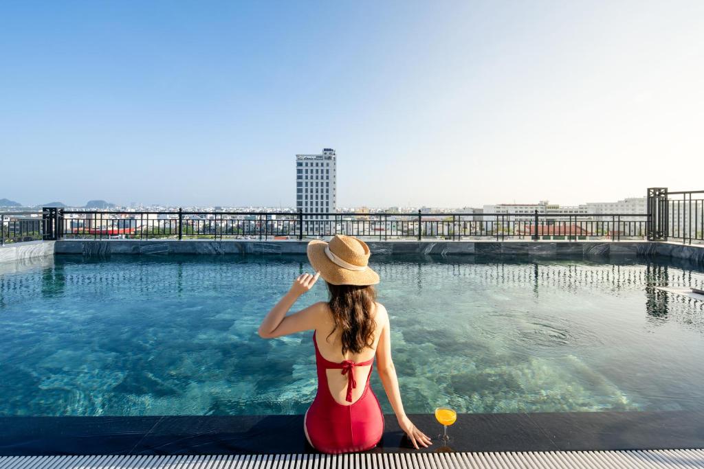 a woman in a hat sitting next to a swimming pool at Tan Phuong Nam Hotel & Apartment in Da Nang