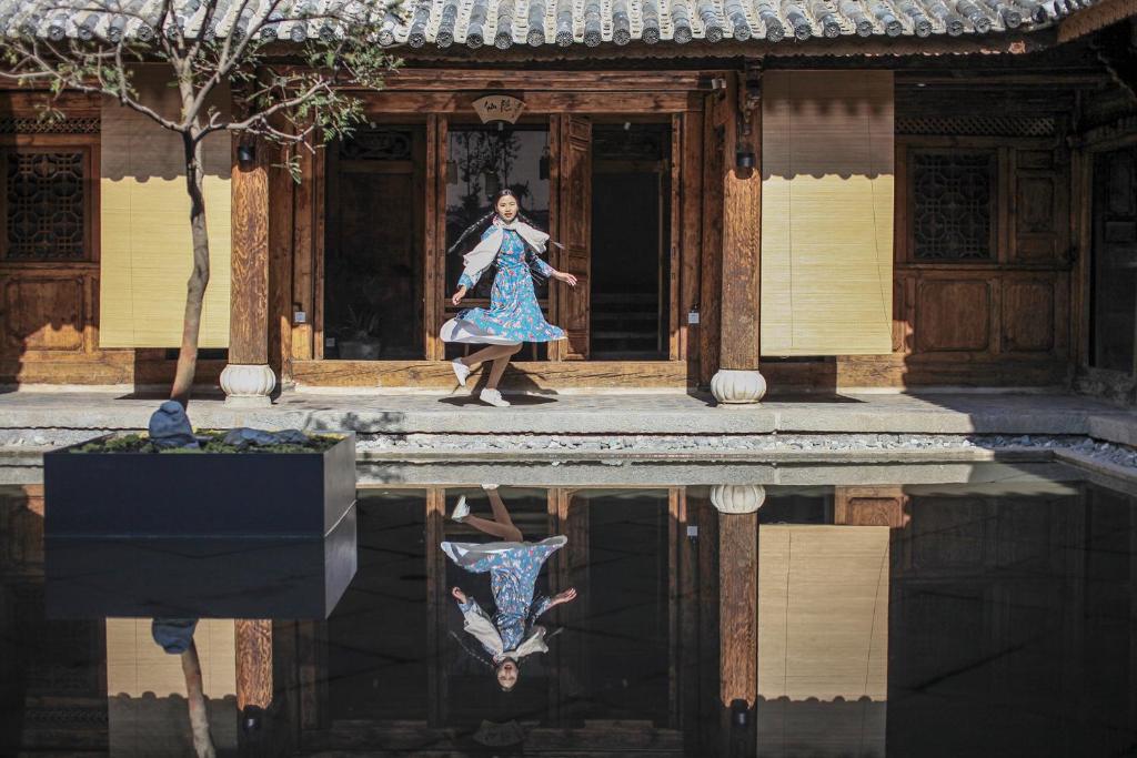 Una mujer con un vestido azul caminando fuera de un edificio en 大理甲科第文化民宿, en Dali