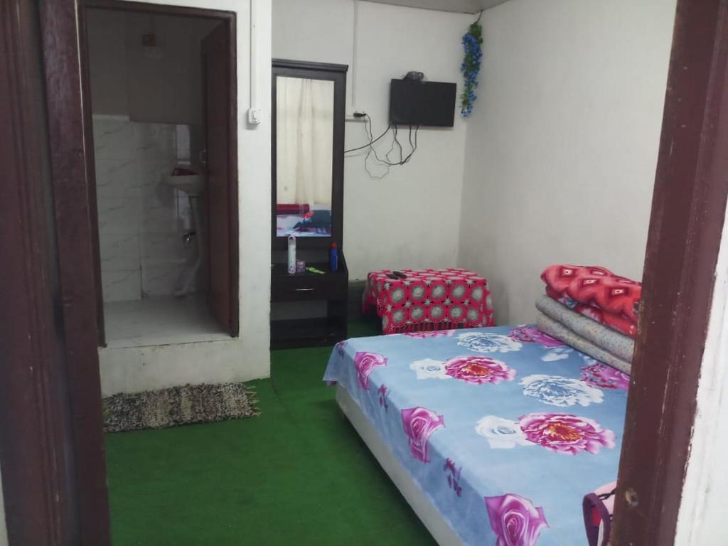 um pequeno quarto com uma cama e um espelho em Vamoose Rhododendron em Darjeeling