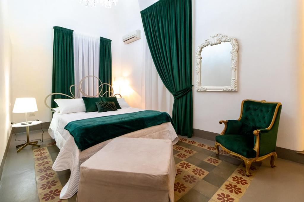 a bedroom with a bed and a chair and a mirror at Pupi e Pupari in Catania