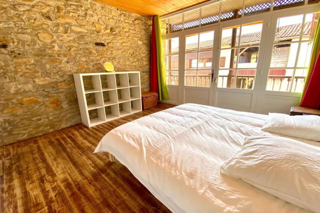 a bedroom with a white bed and a stone wall at Gîte de groupe Petit Moya, Maison de Campagne, 13 personnes. in Arbas