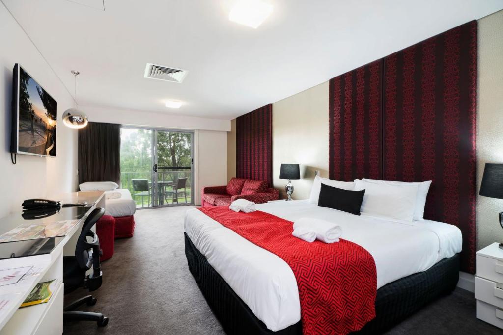 Habitación de hotel con cama grande y sofá en City Golf Club Motel en Toowoomba