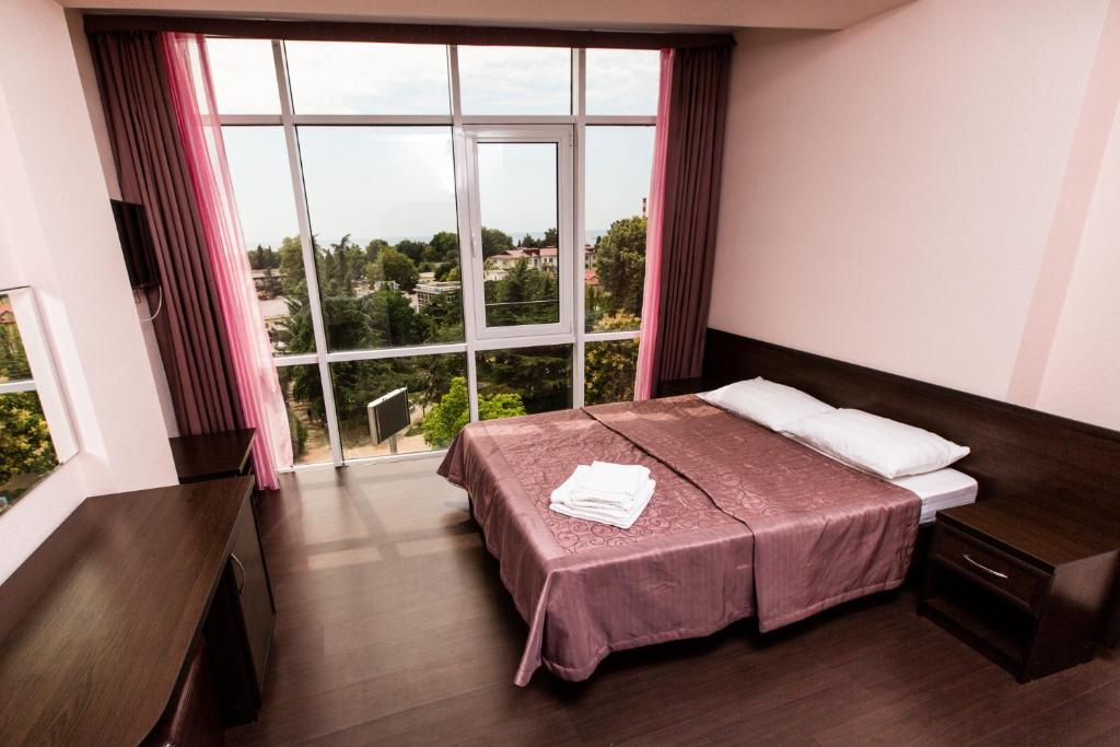 a bedroom with a bed and a large window at Seventh Heaven Hotel in Lazarevskoye
