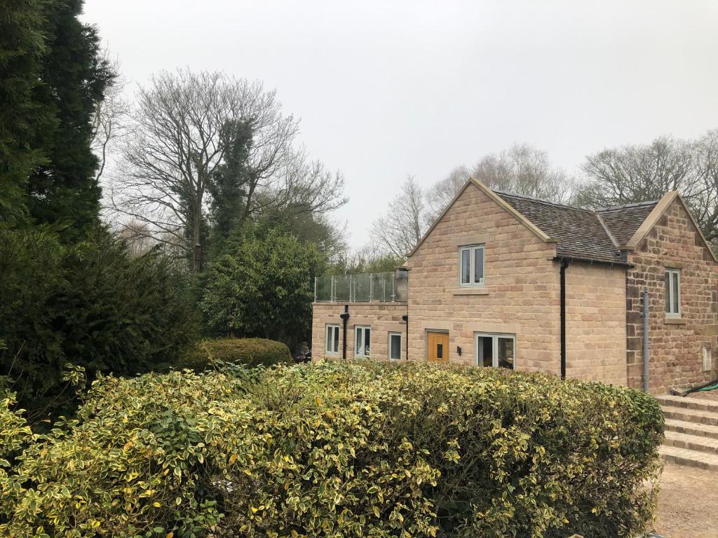 a large brick house with some bushes in front of it at Luxurious Barn Conversion in Oakamoor
