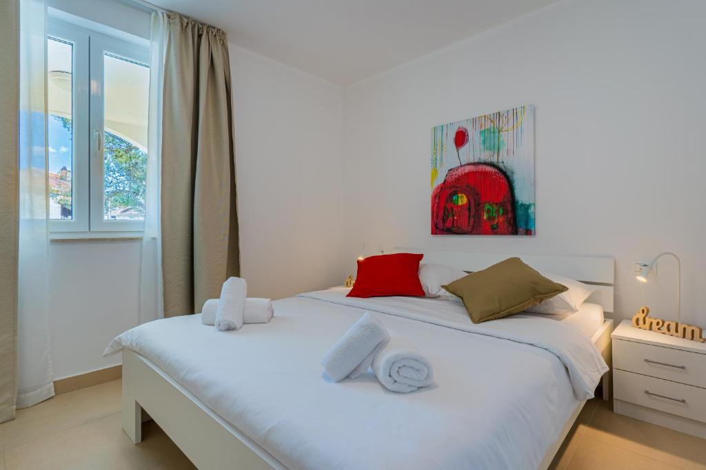 a bedroom with a white bed with towels on it at Apartments Lopari in Nerezine