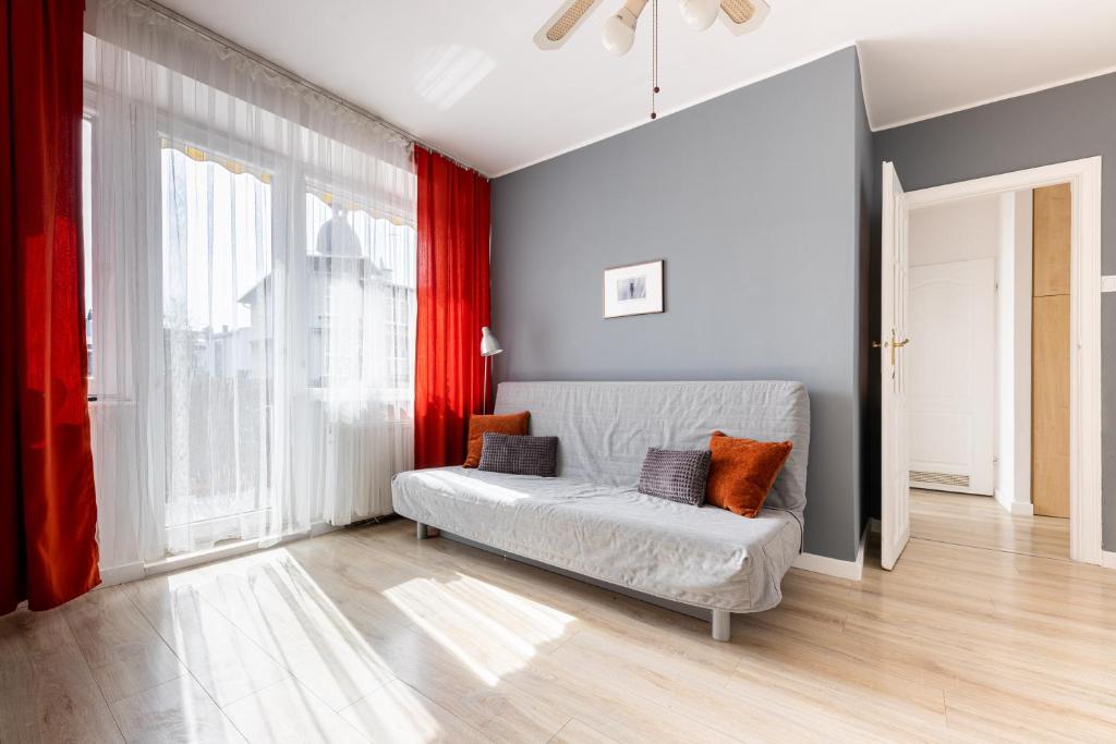 sala de estar con sofá y cortinas rojas en Victus Apartamenty, Apartament Sunshine, en Sopot