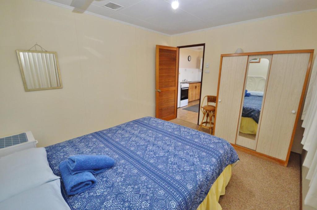 a bedroom with a blue bed and a mirror at Red Rock Retreat C - Kalbarri WA in Kalbarri