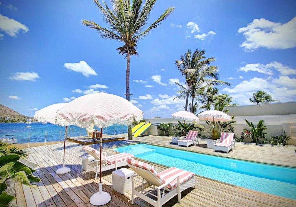 a pool with chairs and umbrellas next to a pool at Villa Horizon Lointain - Private beach and pool with sea view in Cul de Sac