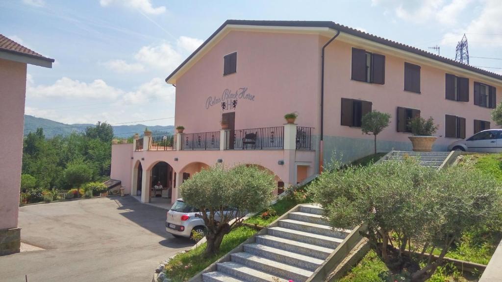 un bâtiment avec une voiture garée devant lui dans l'établissement Relais Black Horse, à Millesimo