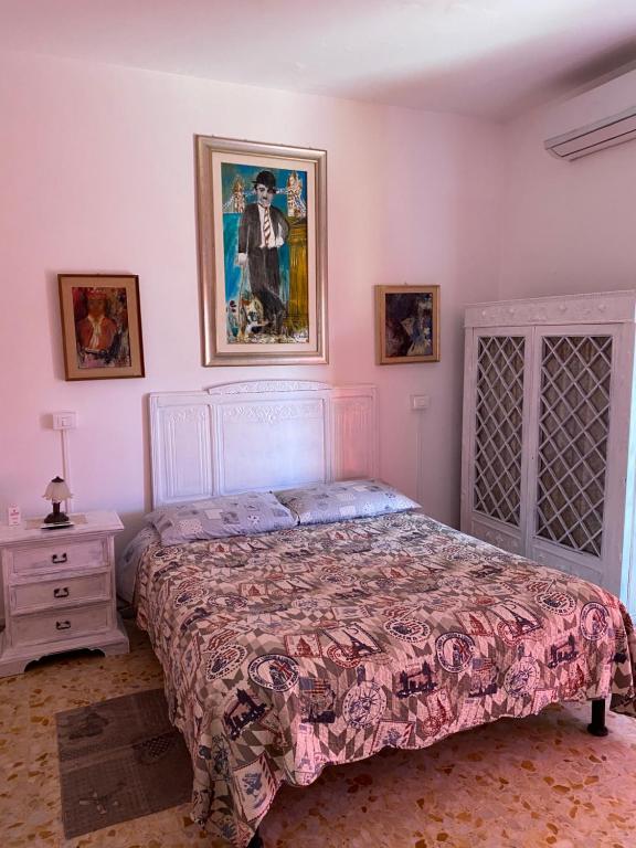 リド・ディ・オスティアにあるAppartamento Zia Gesinaのベッドルーム1室(ベッド1台付)が備わります。壁には絵画が飾られています。
