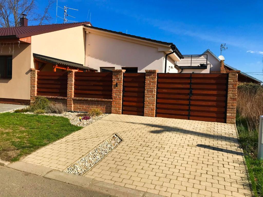 a house with a brick fence and a driveway at Penzion Mikulecký Kutloch in Mikulčice