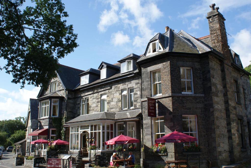 a large stone building with red umbrellas in front of it at Glan Aber Hotel in Betws-y-coed