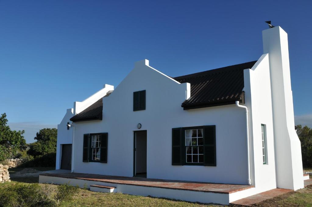 une maison blanche avec un toit noir dans l'établissement De Hoop Collection - Opstal Houses, à De Hoop Nature Reserve