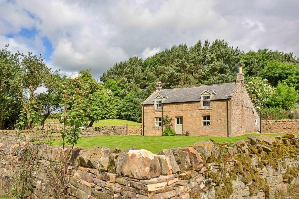 an old stone house behind a stone wall at Finest Retreats - Shortflatt Farm Cottage in Belsay