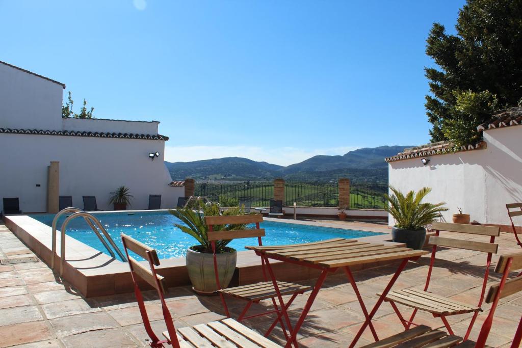 a swimming pool with chairs and a table next to a house at Apartamentos Avanel in Ronda