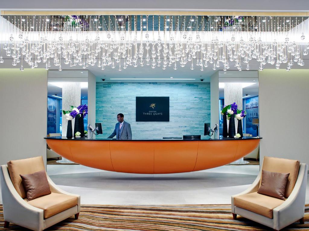 a reception area in a hotel lobby with a large orange desk at Cheval Three Quays at The Tower of London in London