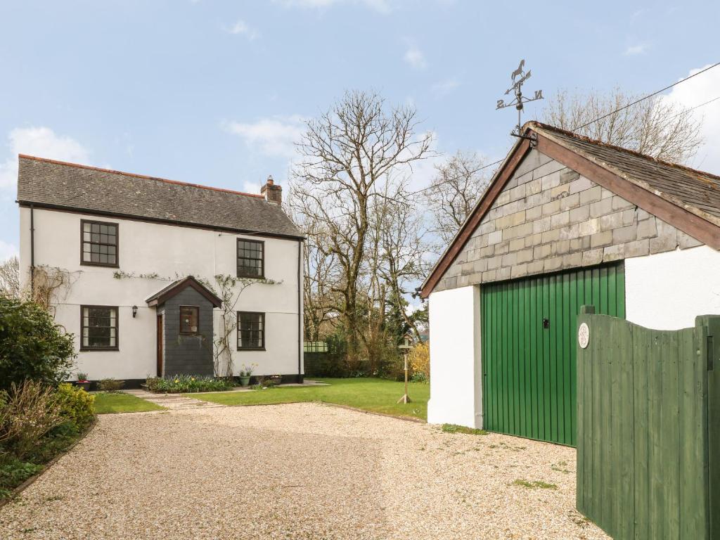 an old white house with a green garage at Thrushel Cottage in Lifton