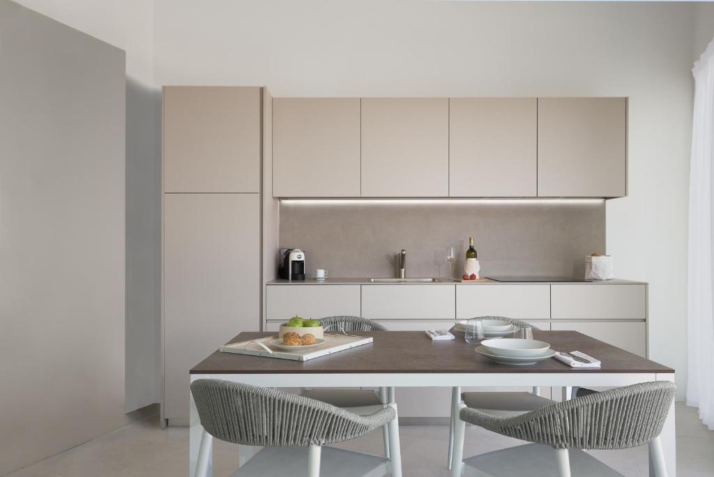 a white kitchen with a table and two chairs at Pareus Beach Resort in Caorle