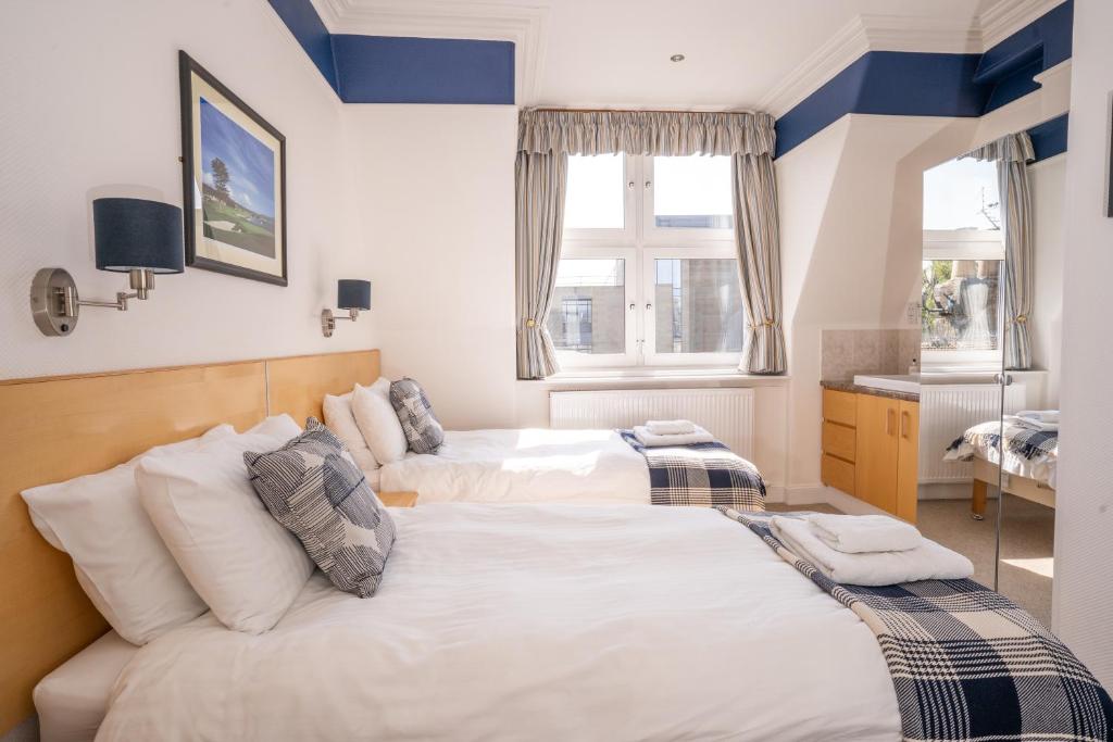2 łóżka w pokoju z niebiesko-białymi ścianami w obiekcie Lorimer House w mieście St Andrews