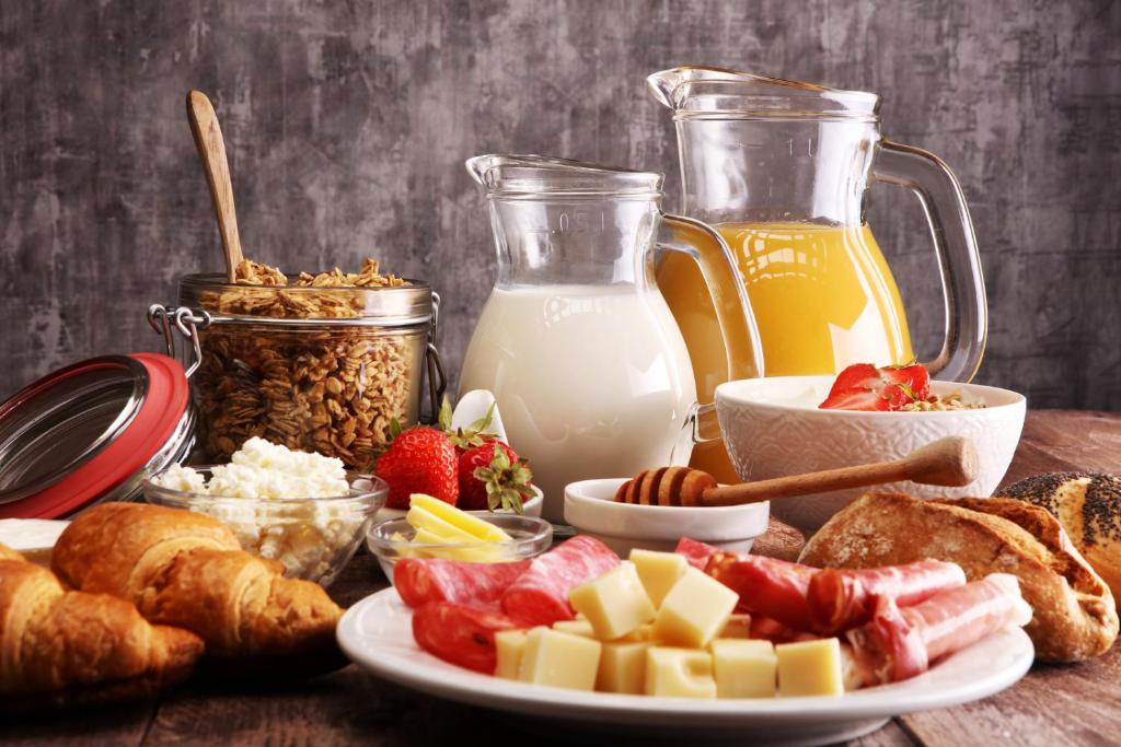 a table with a plate of breakfast foods and milk at Moselblick Hotel Aroma in Burgen