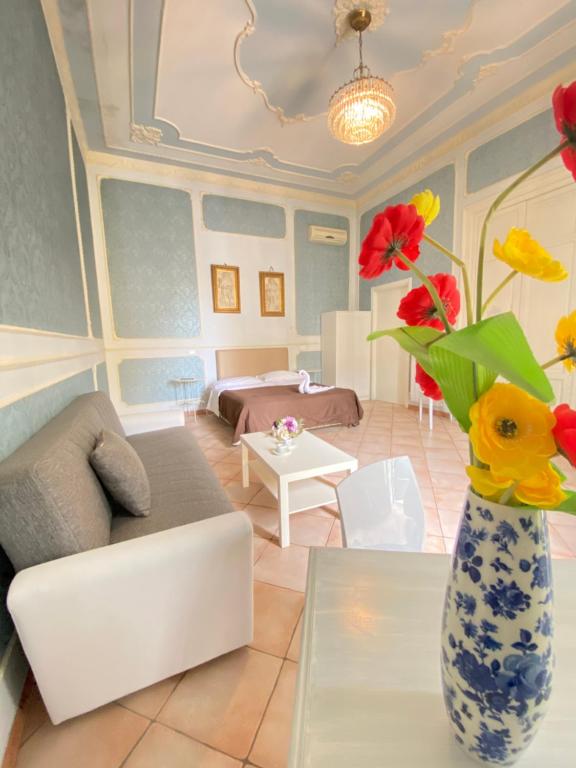 uma sala de estar com um sofá e um vaso de flores em B&B Dimora Annulina em Palermo
