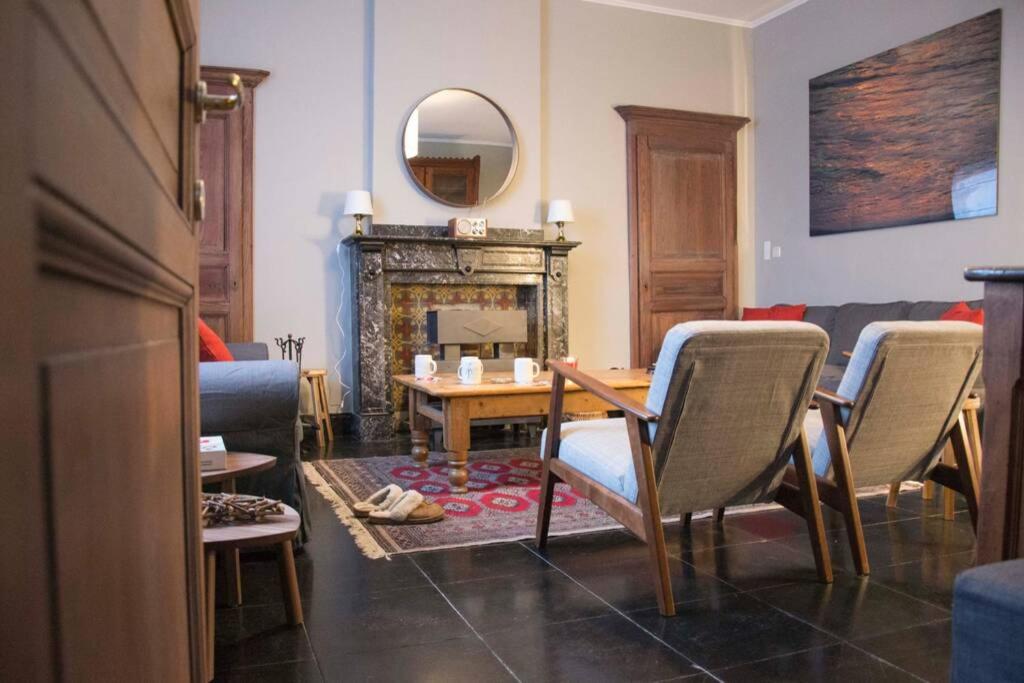 een woonkamer met een tafel en stoelen en een open haard bij Enjoy Square - Spacious Holiday Home near Maredsous in Denée