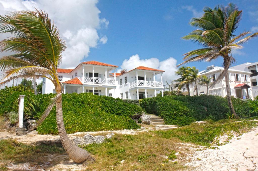 une grande maison blanche avec des palmiers sur la plage dans l'établissement Silver Sands Beach Villas are great for family-friendly activities surfing, à Christ Church