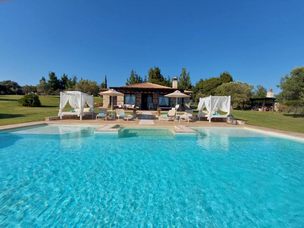 a large swimming pool with chairs and a gazebo at Sithonian Blue Royal Villa in Nikiti