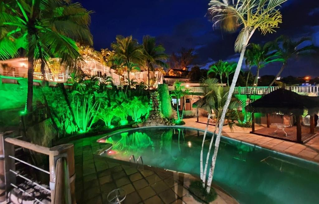 una piscina por la noche con luces verdes en Tarumã Búzios Hotel, en Búzios