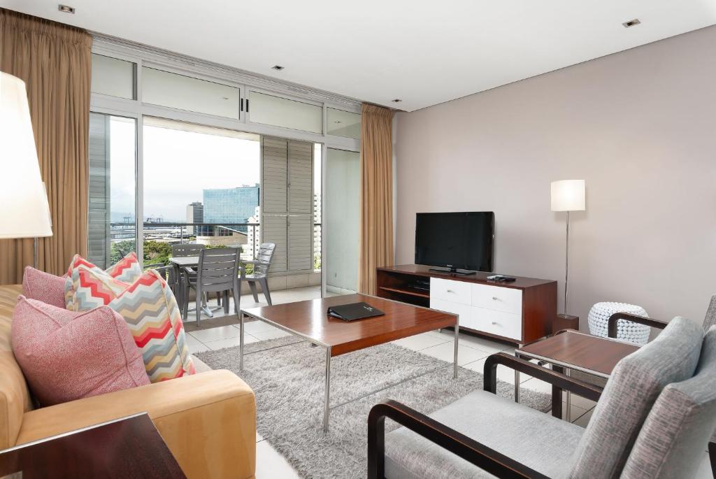 een woonkamer met een bank en een tv bij Kaya Stay in Kaapstad