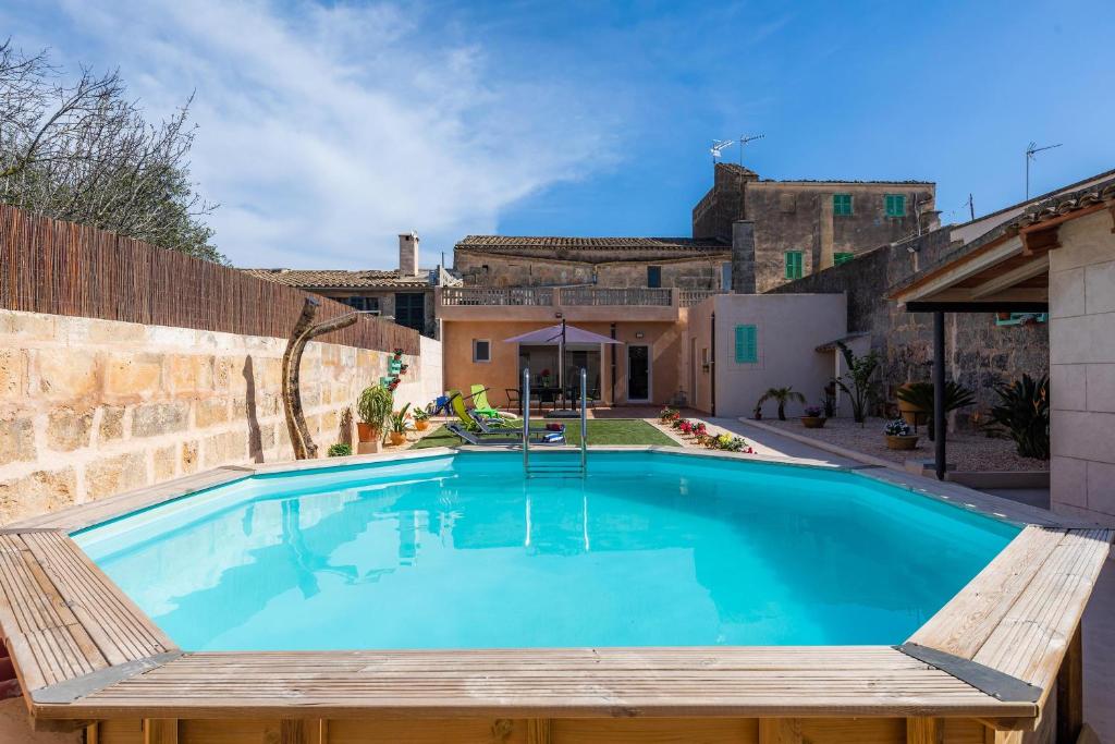 a swimming pool with a wooden bench next to a house at Cas Padri Pep in Ariany